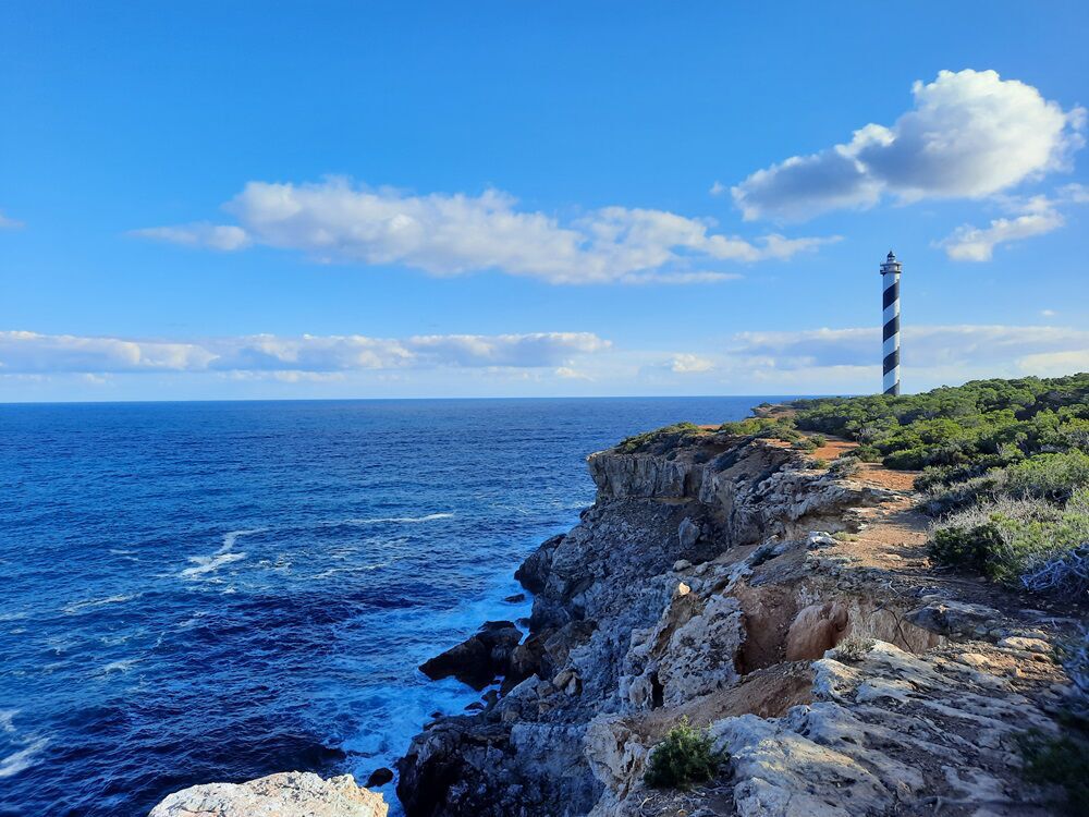 TOWER OF LIGHT — lighthouse trail hike on Ibiza (Easy, 8 km). A striped lighthouse on the northern cliffs at golden hour.
